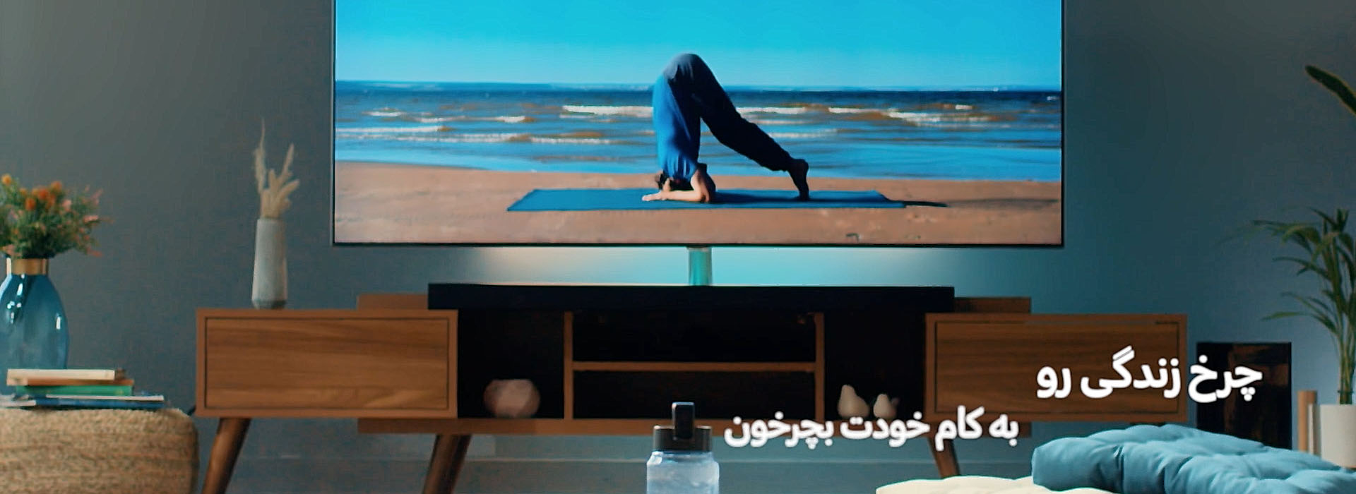 تصویری از یک مانیتور تلویزیون که روی آن یک یوگی در حال حرکت بالانس روی دستانش است