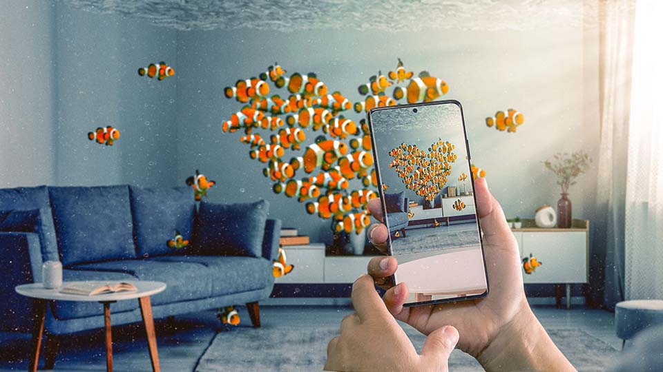 A school of clownfish forming a heart shape in a living room - a hand is seen photographing them with a Samsung phone