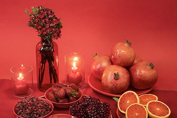 A traditional Yalda night table with the dominant red color; flowers, pomegranates, and other fruits
